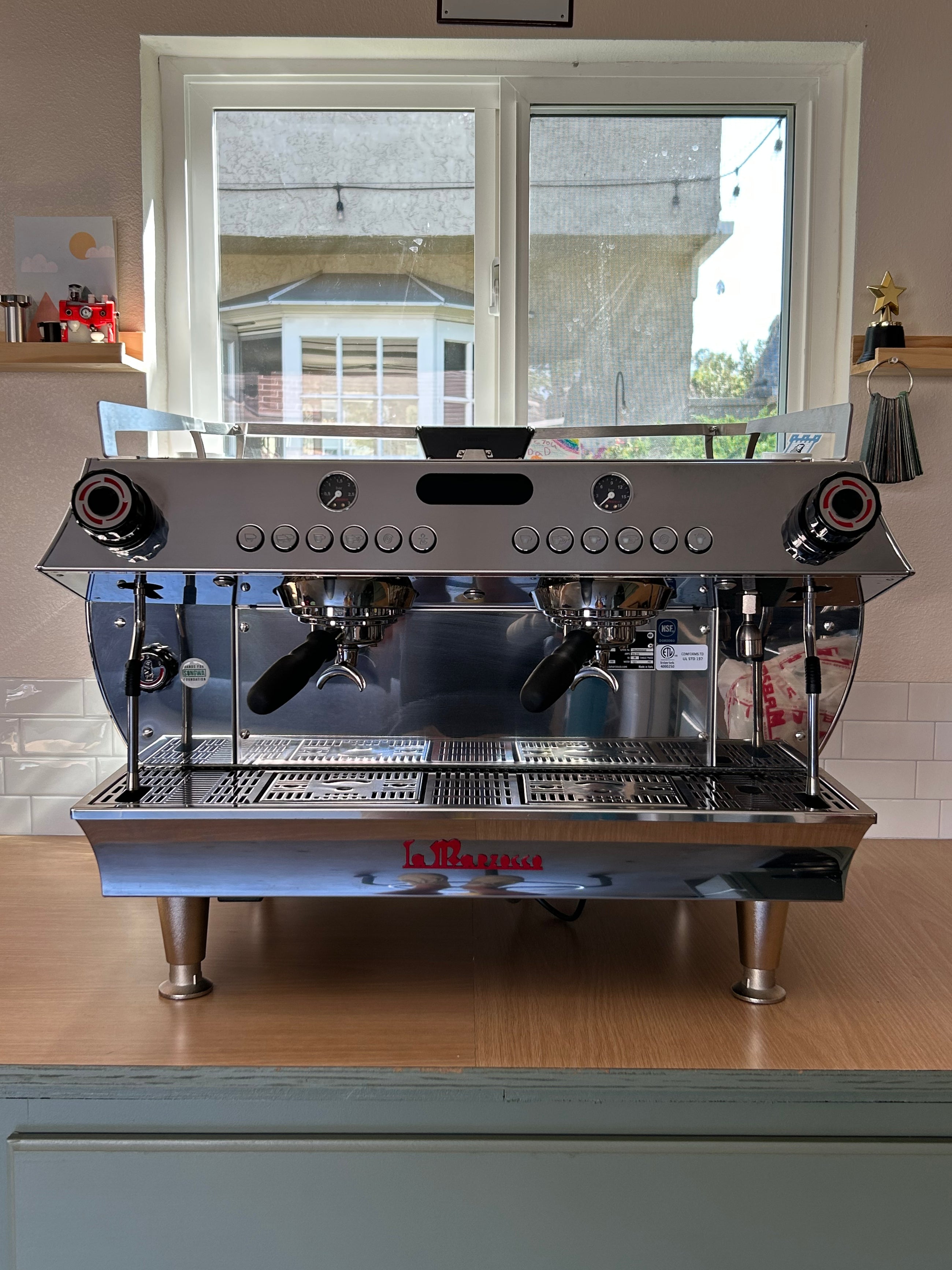 Commercial espresso machine on a wooden counter with a window in the background