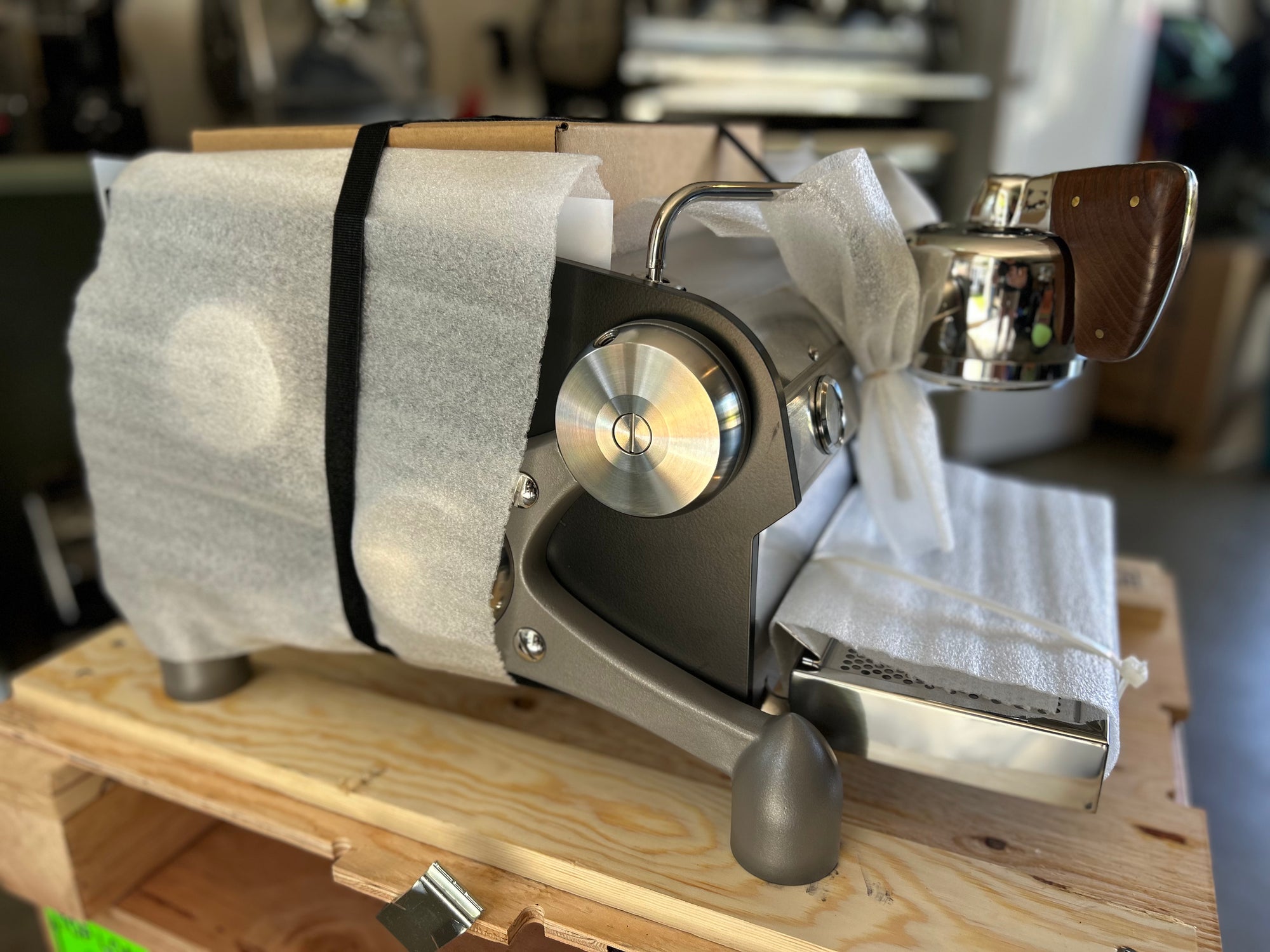 Slayer Espresso Single wrapped in protective paper on a wooden surface with a blurred background