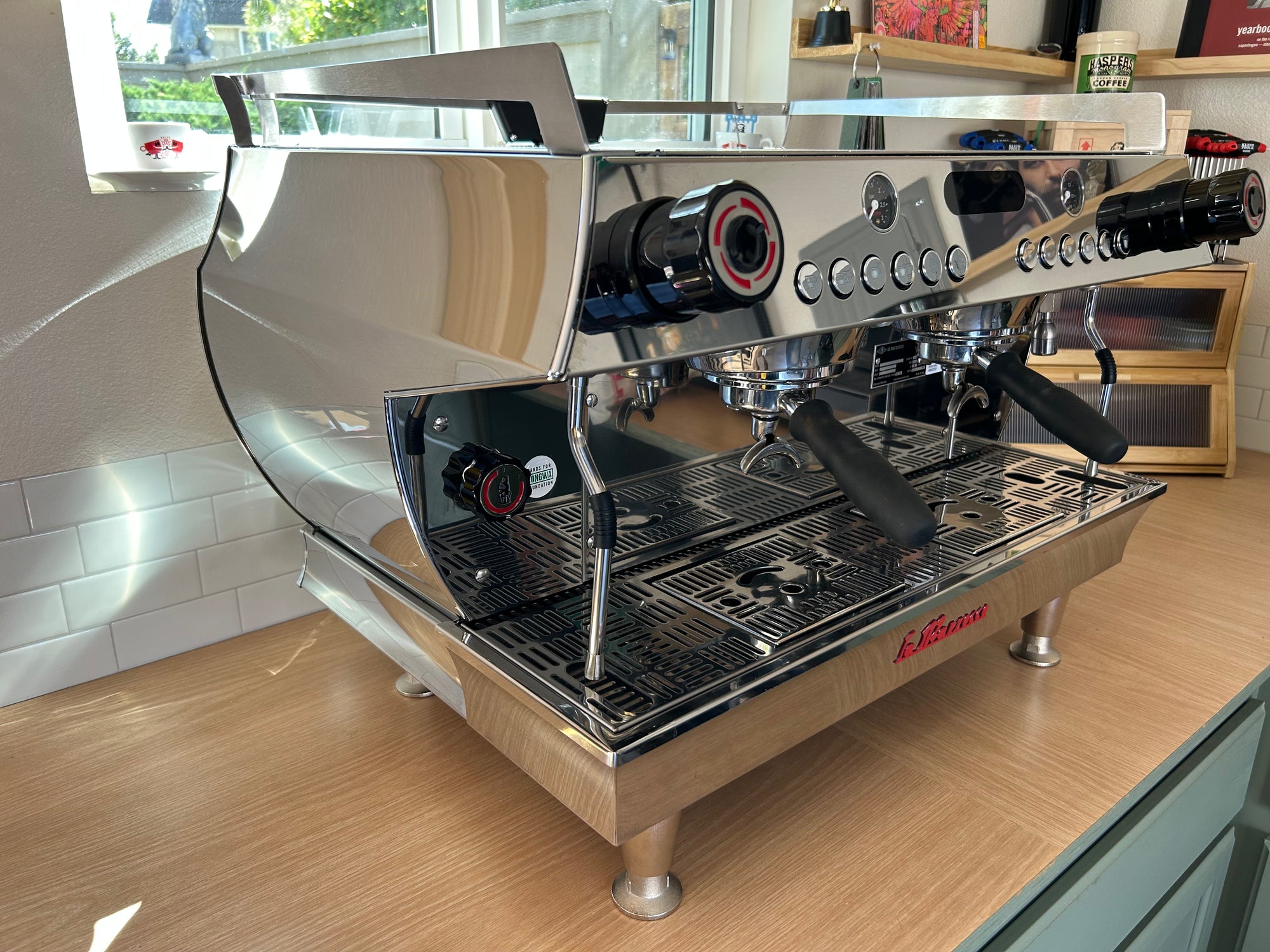 Stainless steel espresso machine on a wooden counter with a blurred background