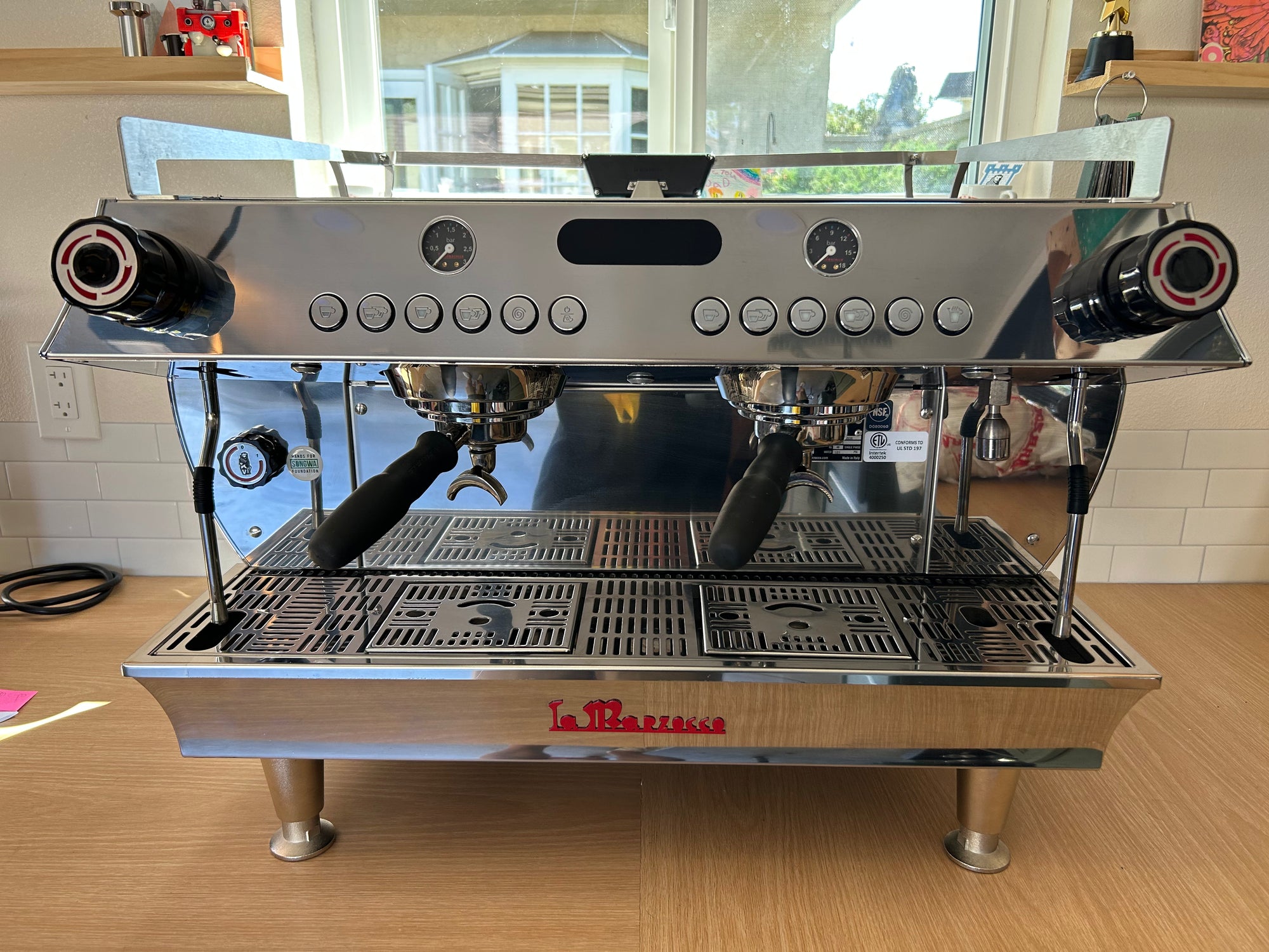 La Marzocco coffee machine on a wooden floor with a window in the background