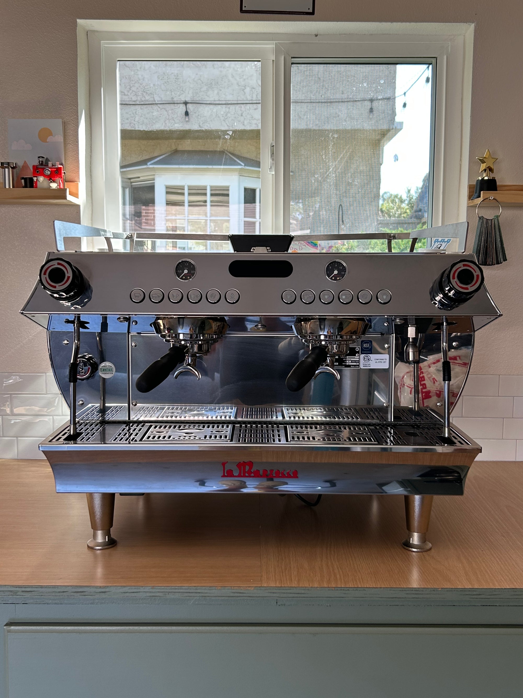 Commercial espresso machine on a wooden counter with a window in the background