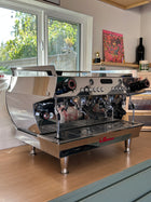 Espresso machine on a wooden counter with a window and decor in the background