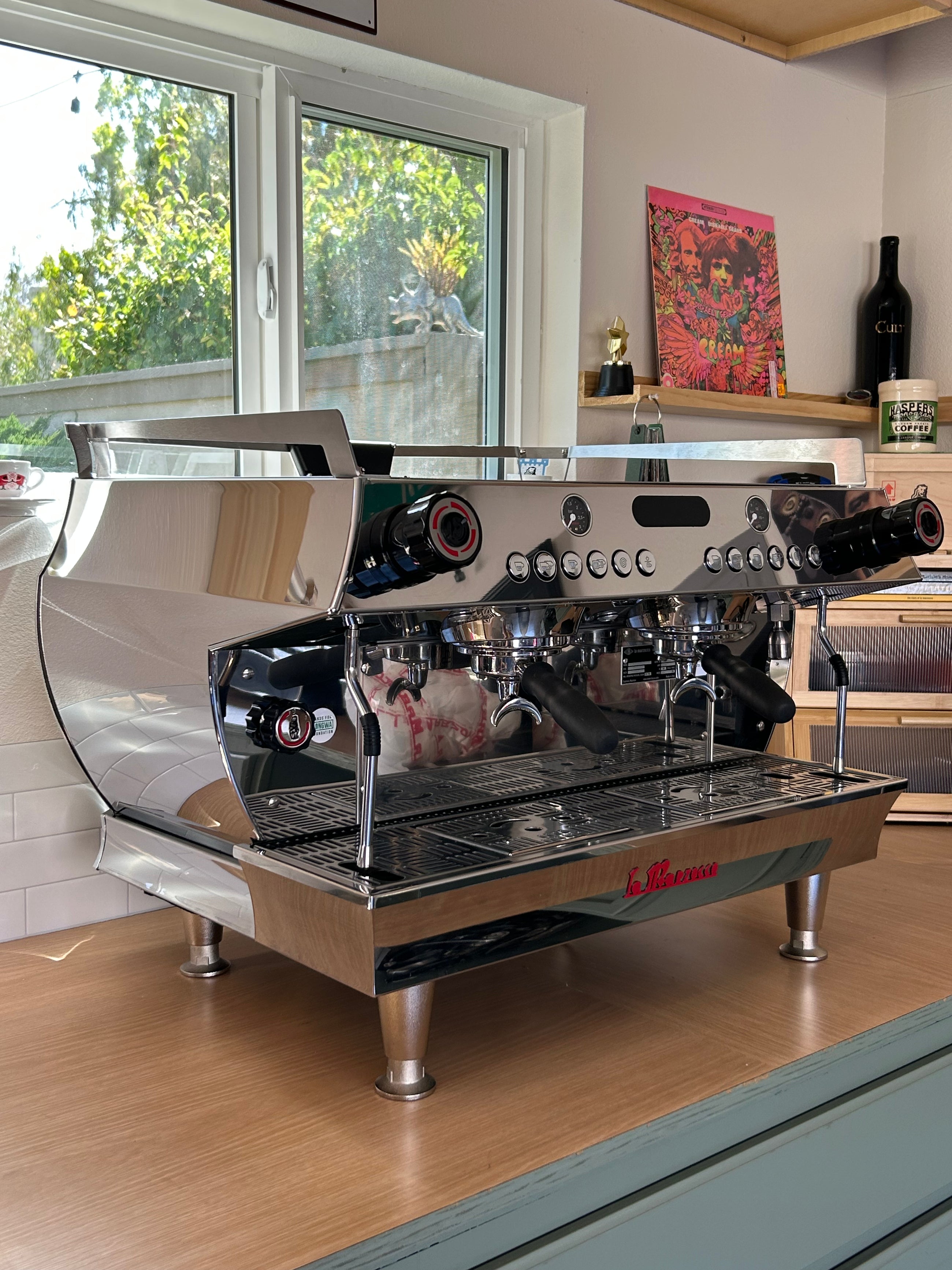 Espresso machine on a wooden counter with a window and decor in the background